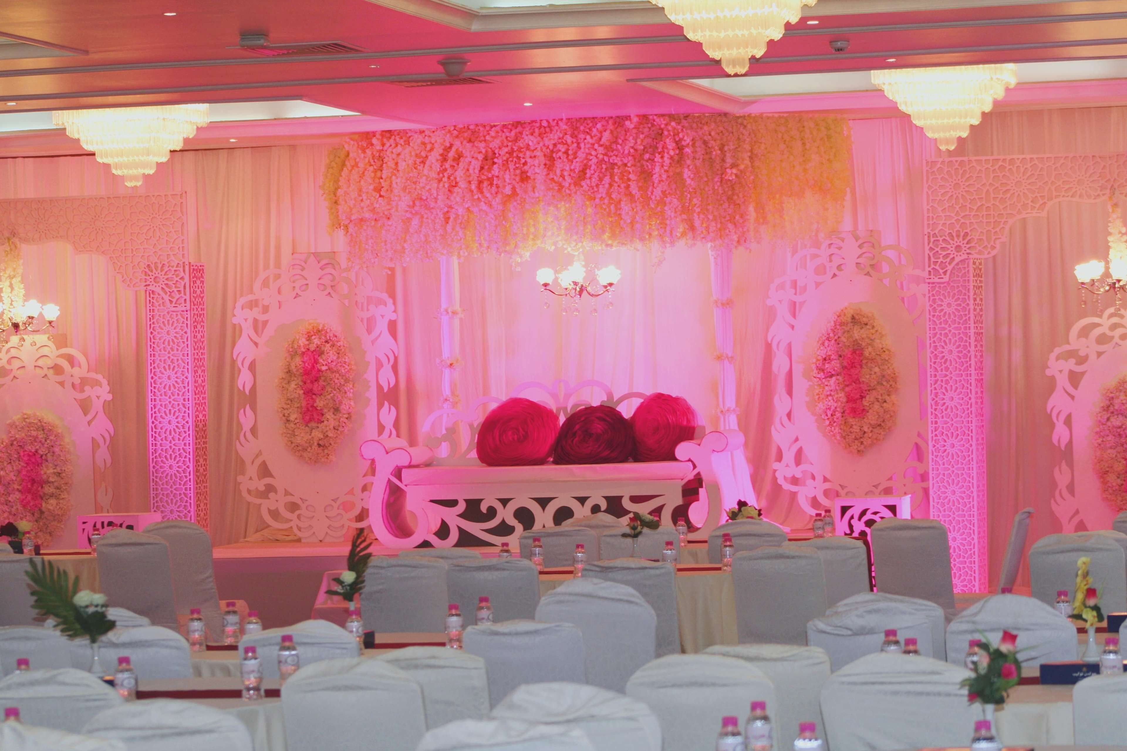 Un salón de banquetes con escenario, sillas y mesas dispuestas para un evento.