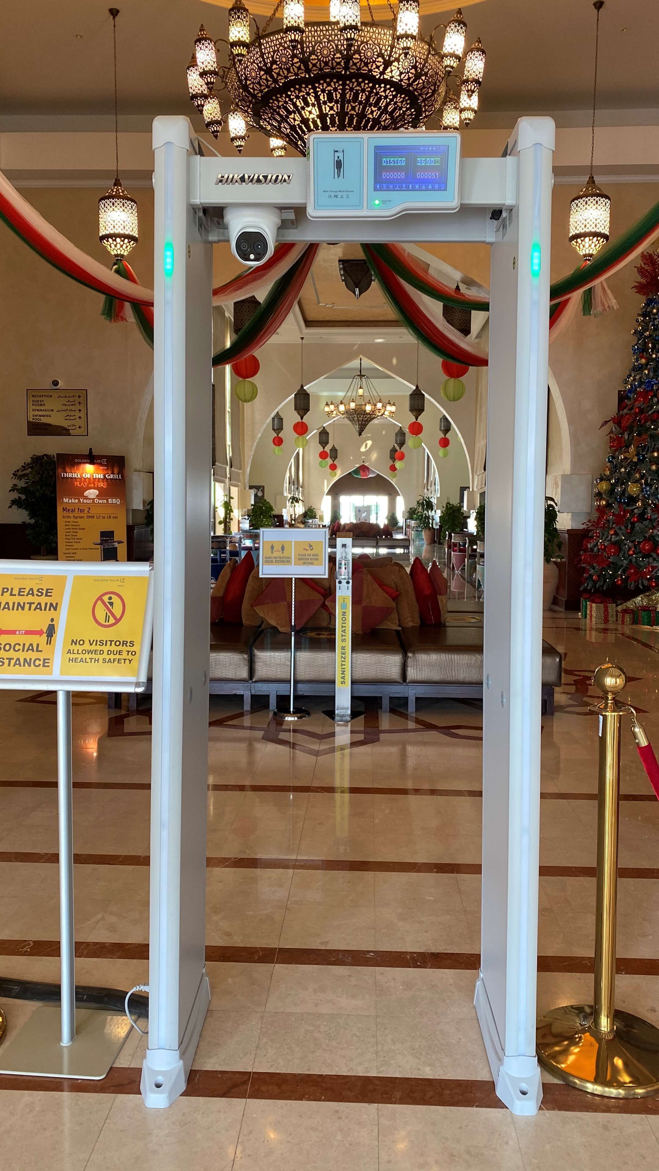 Un hall d’hôtel comprenant un comptoir d’accueil, des panneaux d’orientation, un sapin de Noël et un espace salon agrémenté d’un lustre.