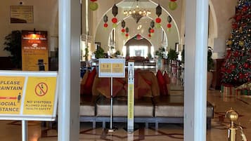 Un hall d’hôtel comprenant un comptoir d’accueil, des panneaux d’orientation, un sapin de Noël et un espace salon agrémenté d’un lustre.