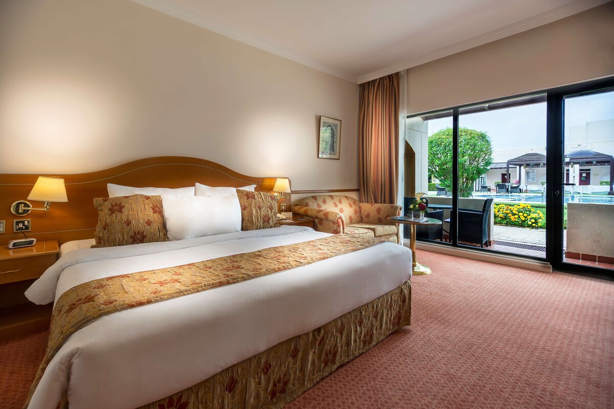 Une chambre d’hôtel avec un grand lit, un bureau, une chaise et une vue sur l’espace extérieur.