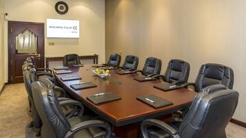 A conference room with a long table, eight black leather chairs, and a whiteboard on the wall.