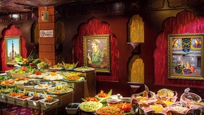 Buffet com diversos pratos e decorações culturais.