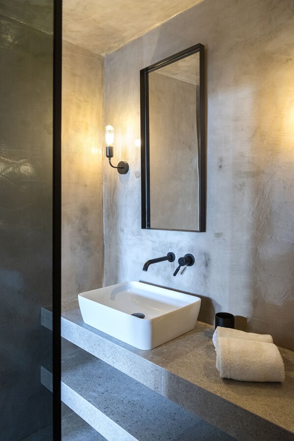 A modern bathroom with a white sink, a large mirror, and a towel on the counter.