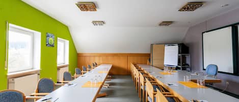 Une salle de conférence équipée d’une longue table, de chaises, d’un tableau blanc et d’un écran de projection.
