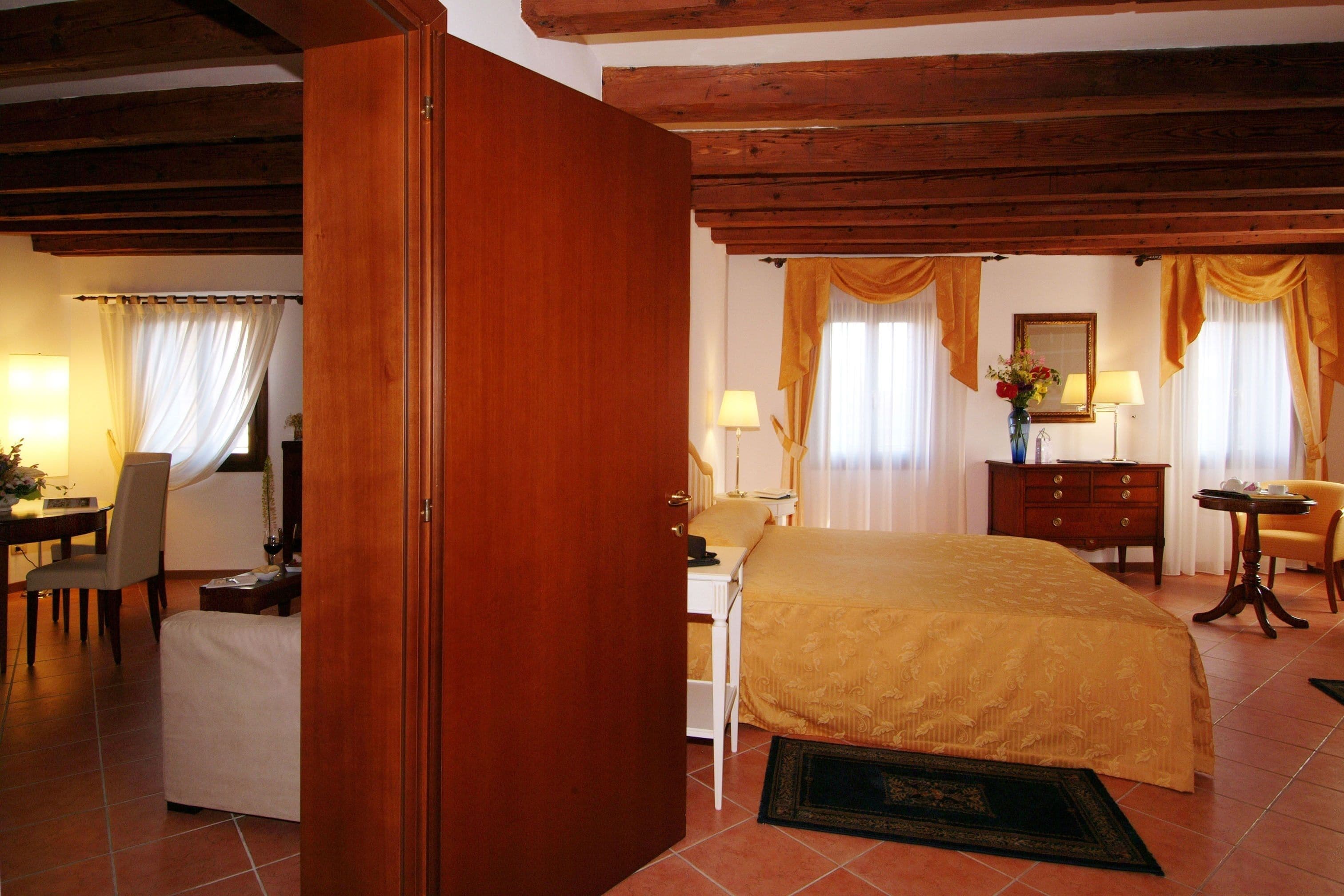 Una habitación de hotel con cama, escritorio, silla, cómoda y zona de comedor.