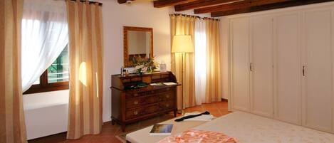 Un dormitorio con cama, cómoda, espejo y cortinas.