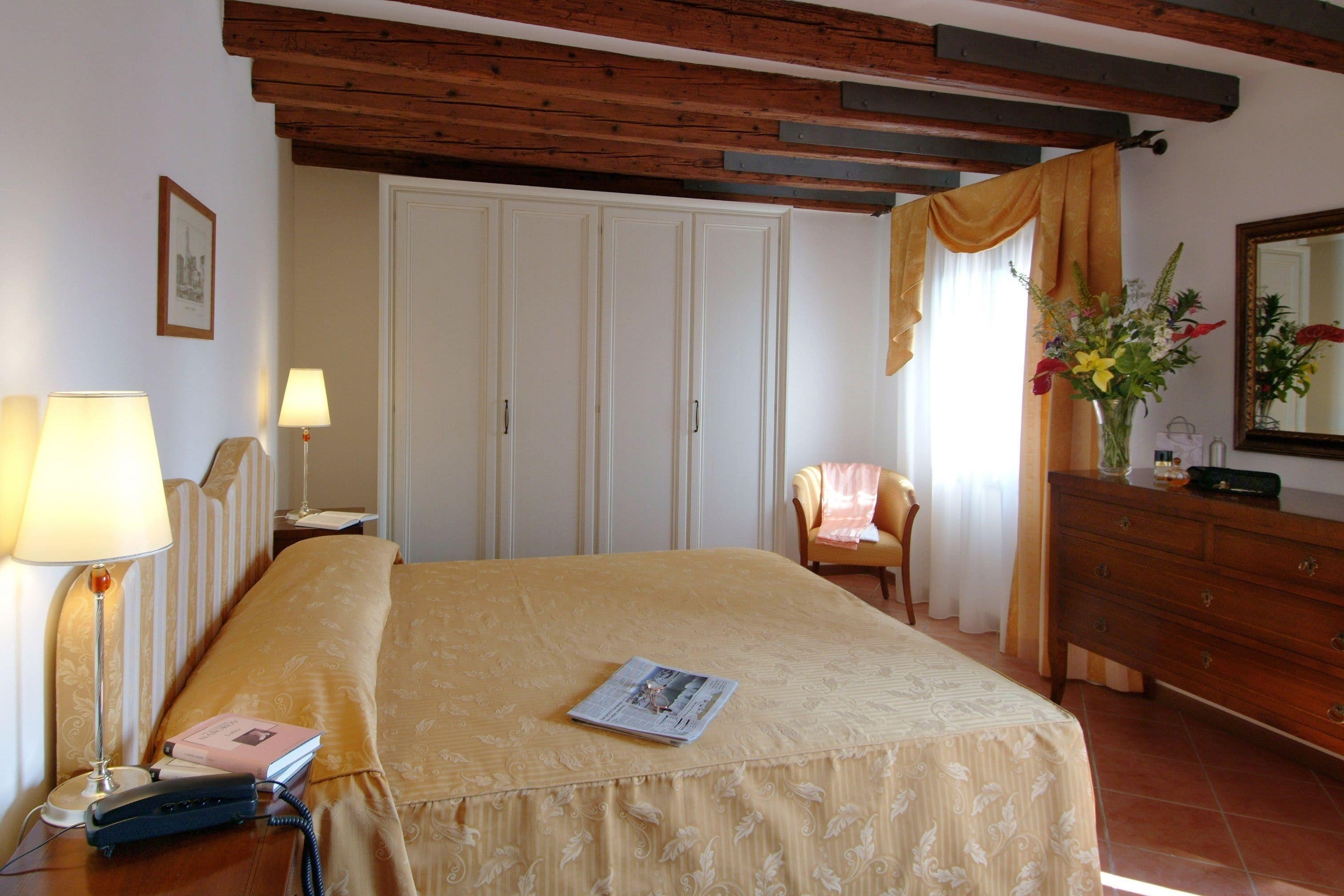 Een hotelkamer met een bed, nachtlampjes, een kaptafel, een stoel en een spiegel.