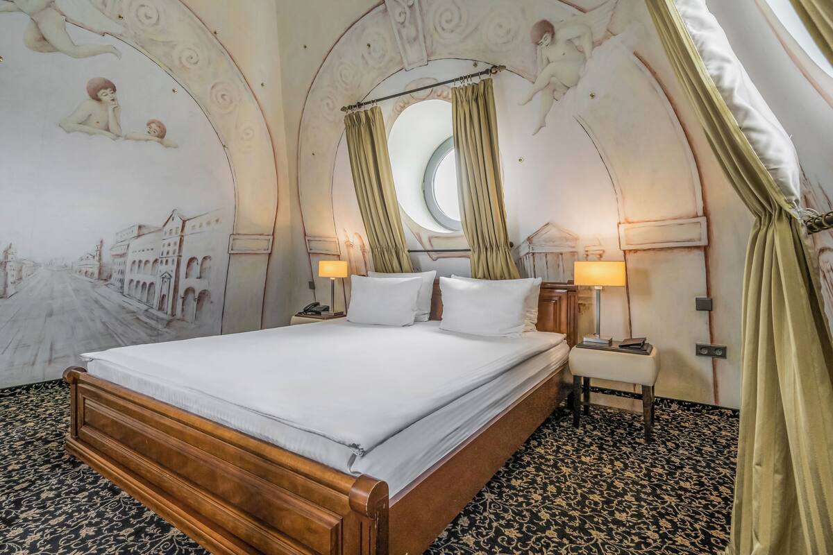 Una camera da letto con un letto grande, due lampade sui comodini, un comodino e una finestra con tende.