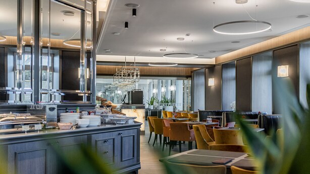 Un ristorante moderno con un'isola centrale, zona con posti a sedere e ampie finestre.