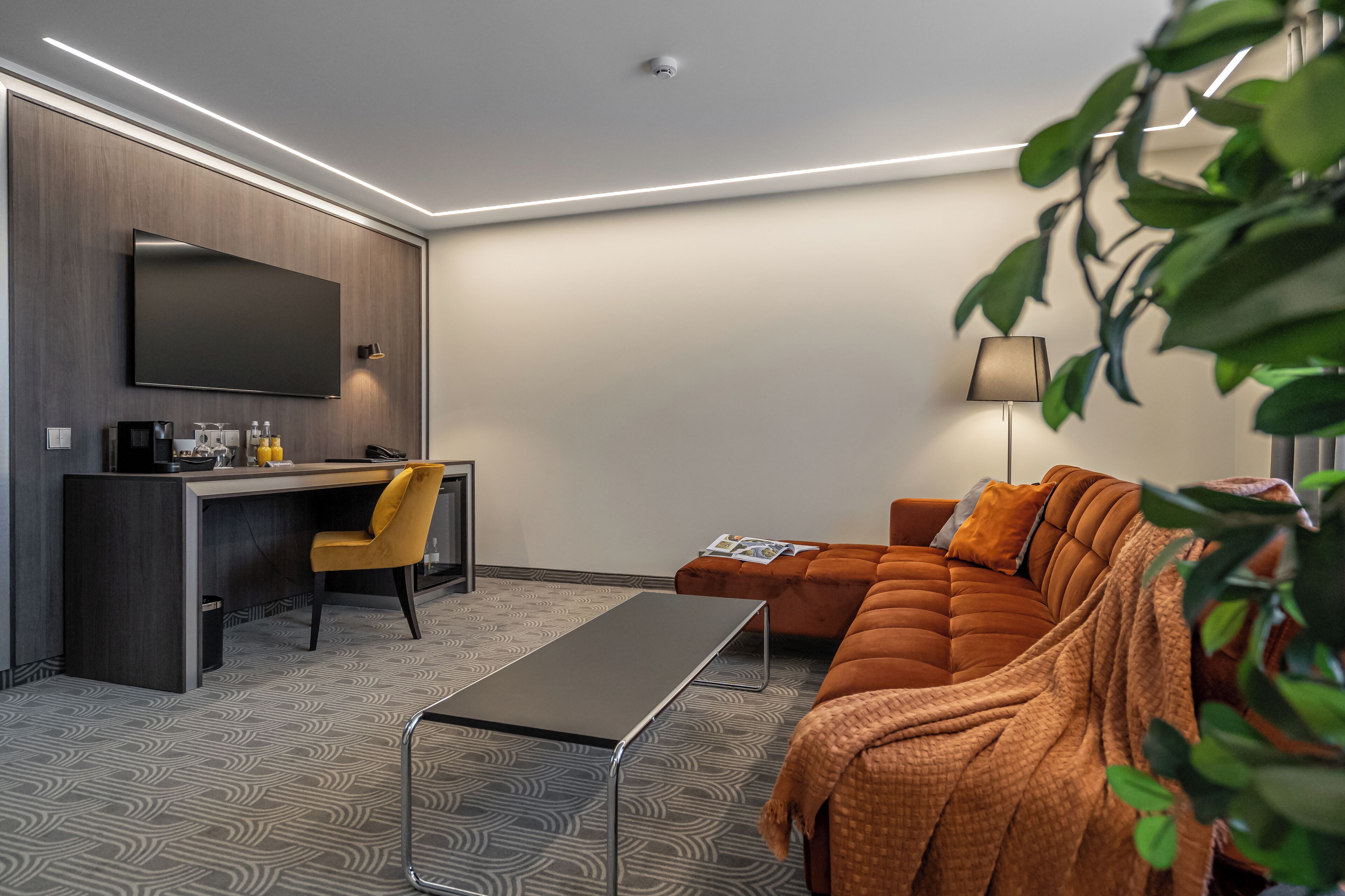 A modern living room with a sofa, a coffee table, a TV, and a desk with a chair.