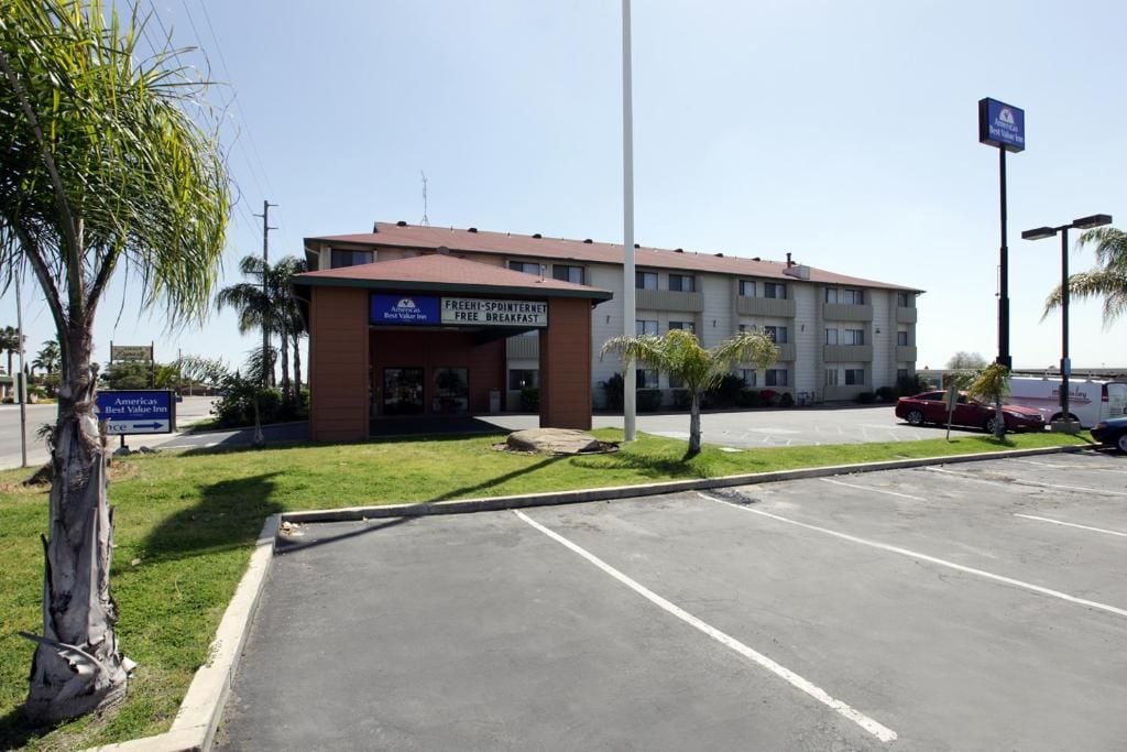 Un hotel con un letrero que anuncia desayuno gratuito, un estacionamiento y un edificio de techo rojo.