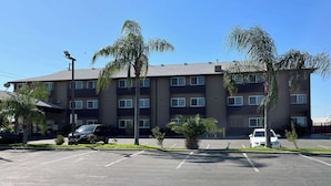 A multi-story hotel with a parking lot in front. - Studio 6 Suites Delano, CA (Delano)