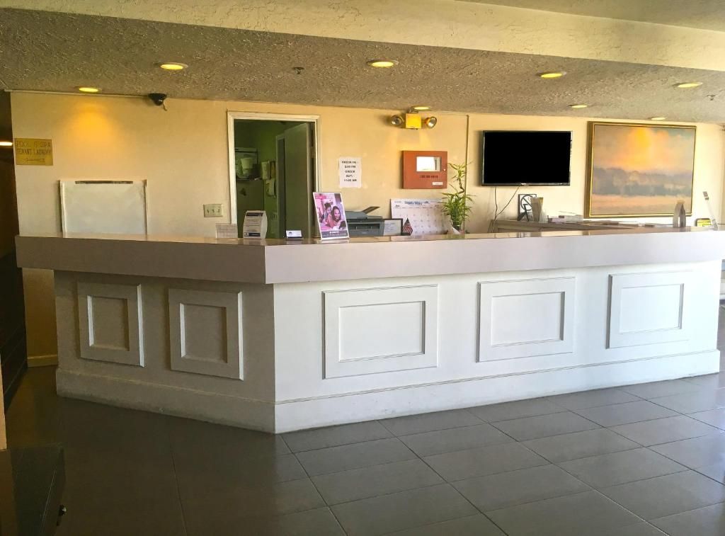 A reception desk with a flat-screen TV, a plant, and a calendar.