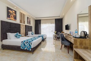 A hotel room with a large bed, a desk, a chair, a TV, and artwork on the walls. - Seagull Beach Resort Families & Couples Only - All Inclusive (Hurghada)