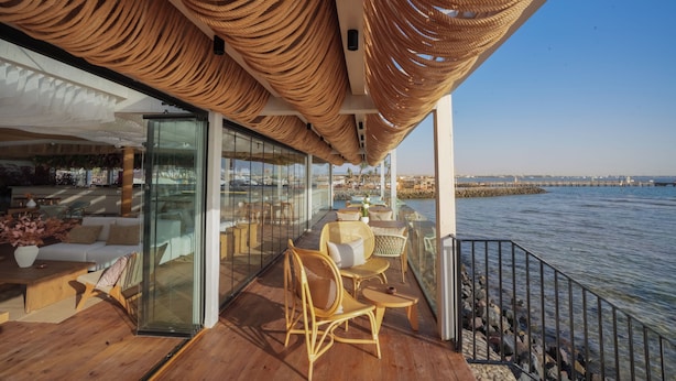 A wooden deck with wicker furniture overlooking a waterfront. - Desert Rose  (Hurghada)