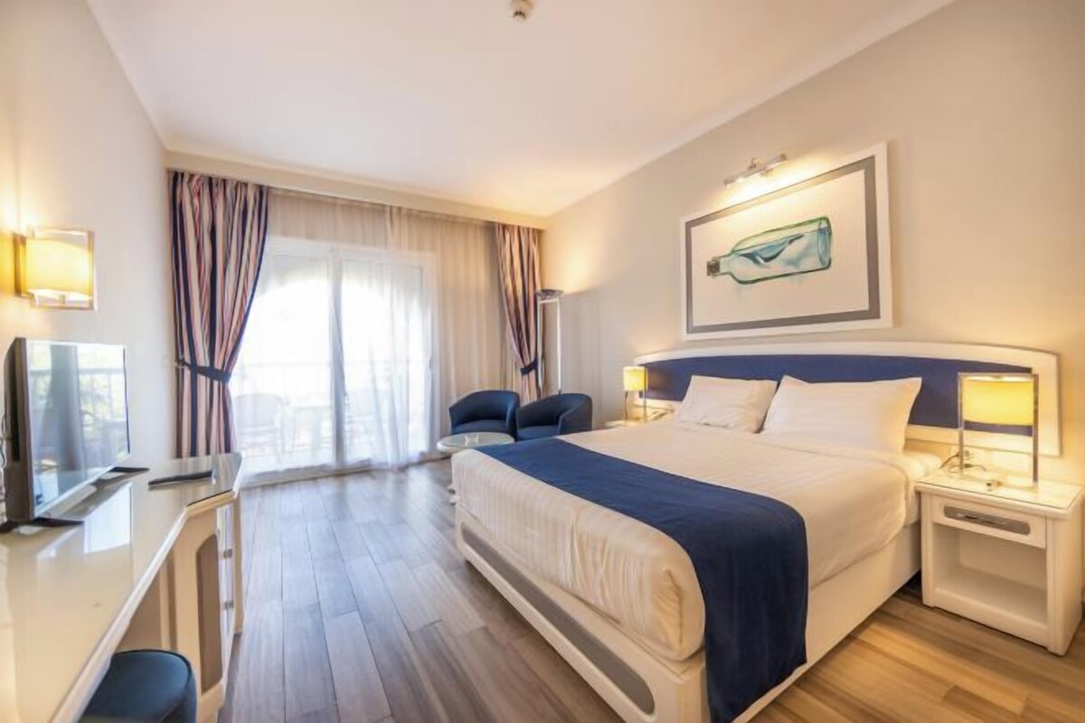 Een hotelkamer met een bed, nachtkastjes, een bureau, een stoel en een televisie.
