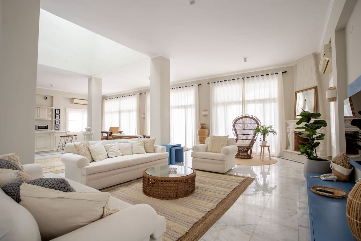 A spacious living room with a large white sofa set, a coffee table, and a blue accent wall.