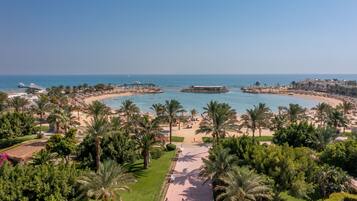 Un complejo turístico en la costa con playa, palmeras y un muelle.