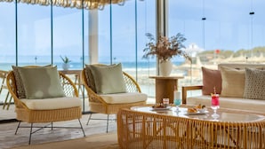 A beachside lounge with wicker furniture, a round table with drinks, and a view of the ocean. - Desert Rose  (Hurghada)