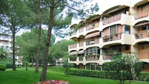 A multi-story hotel with balconies, surrounded by well-maintained lawns and trees. - Résidence Lagrange Vacances Les Trois Rivières (Mandelieu-La-Napoule)