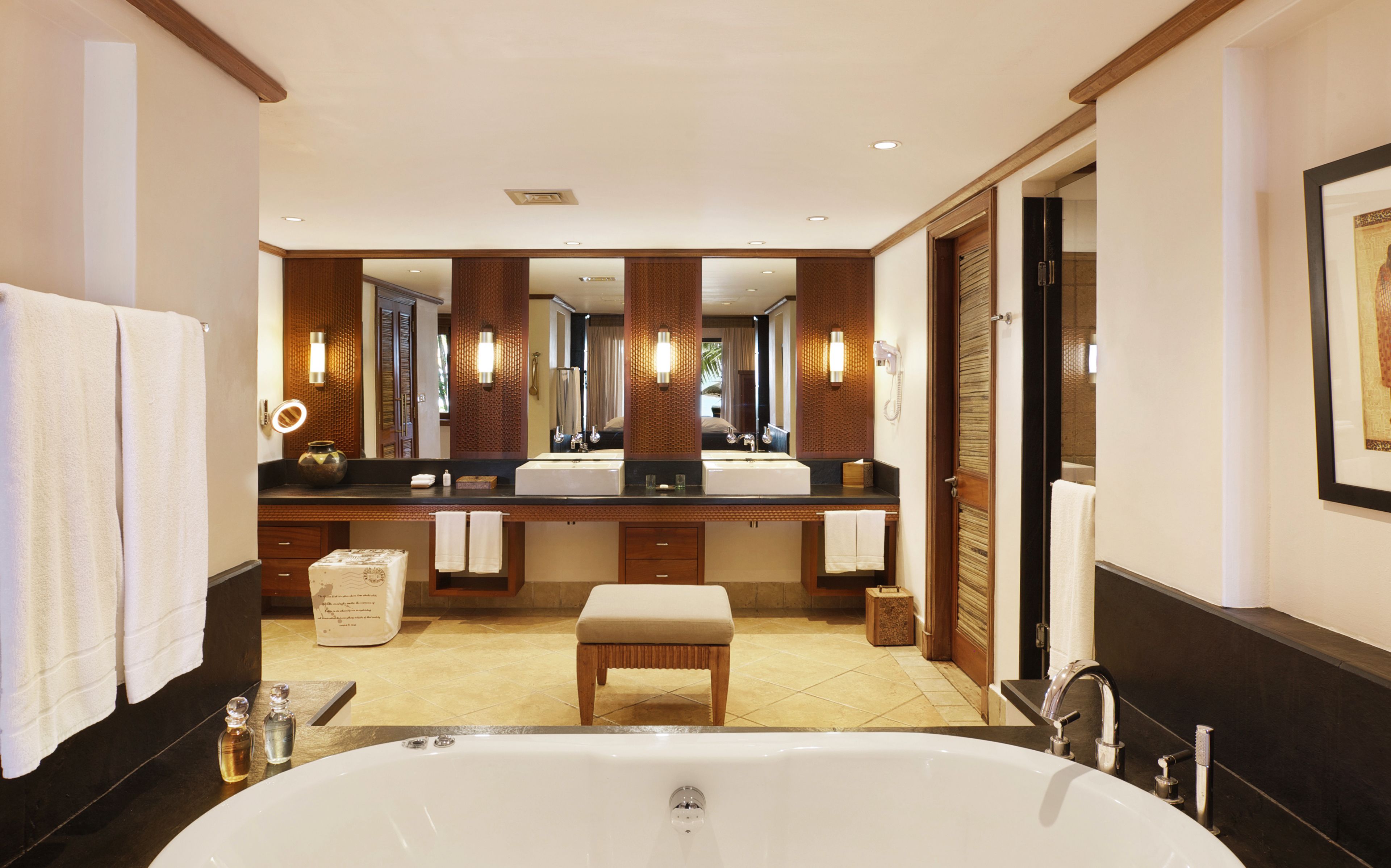 Un baño moderno con una bañera grande, lavamanos dobles y un tocador con espejo.