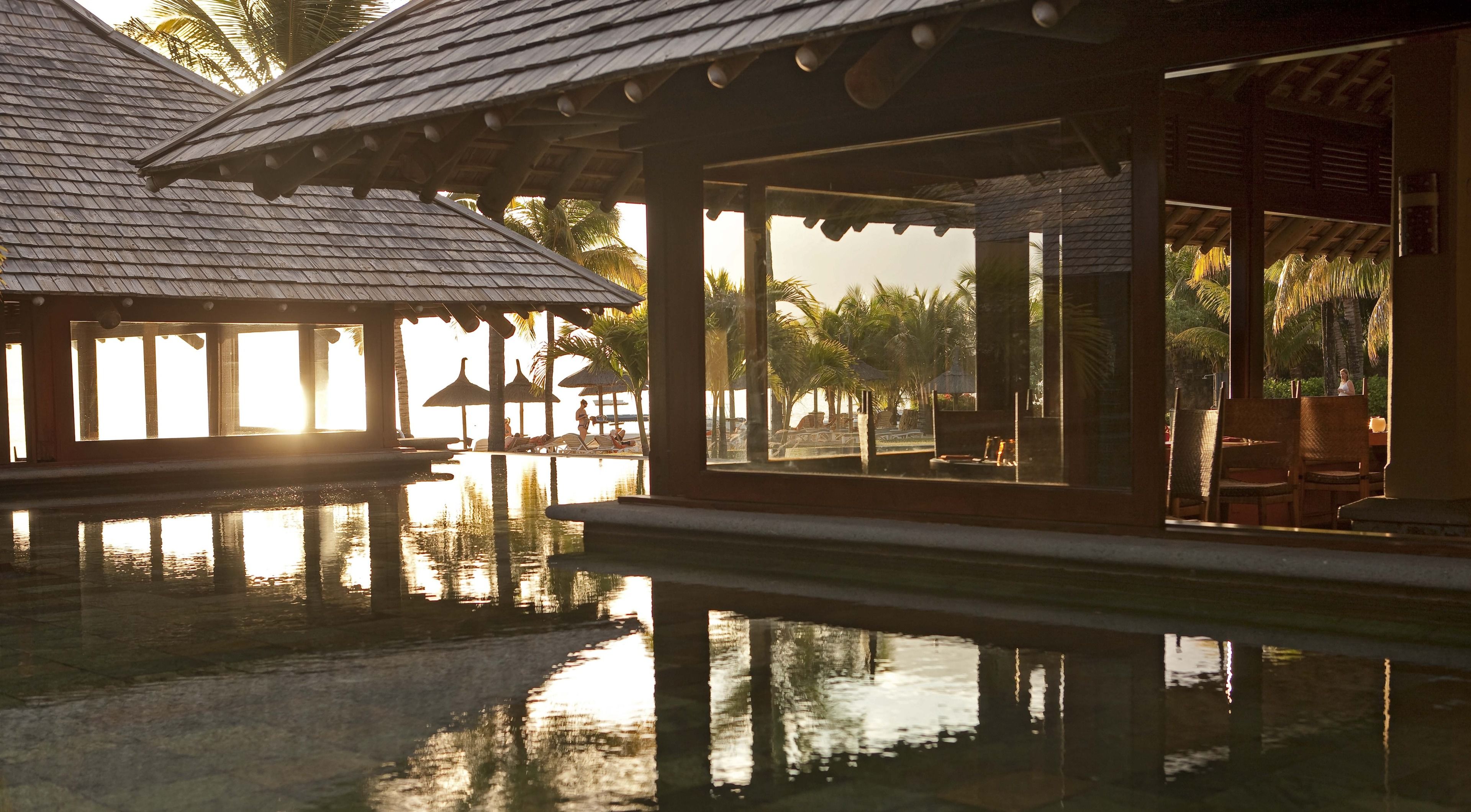 A resort with a pool, wooden structures, and palm trees.