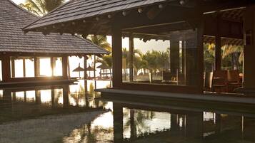 A resort with a pool, wooden structures, and palm trees.