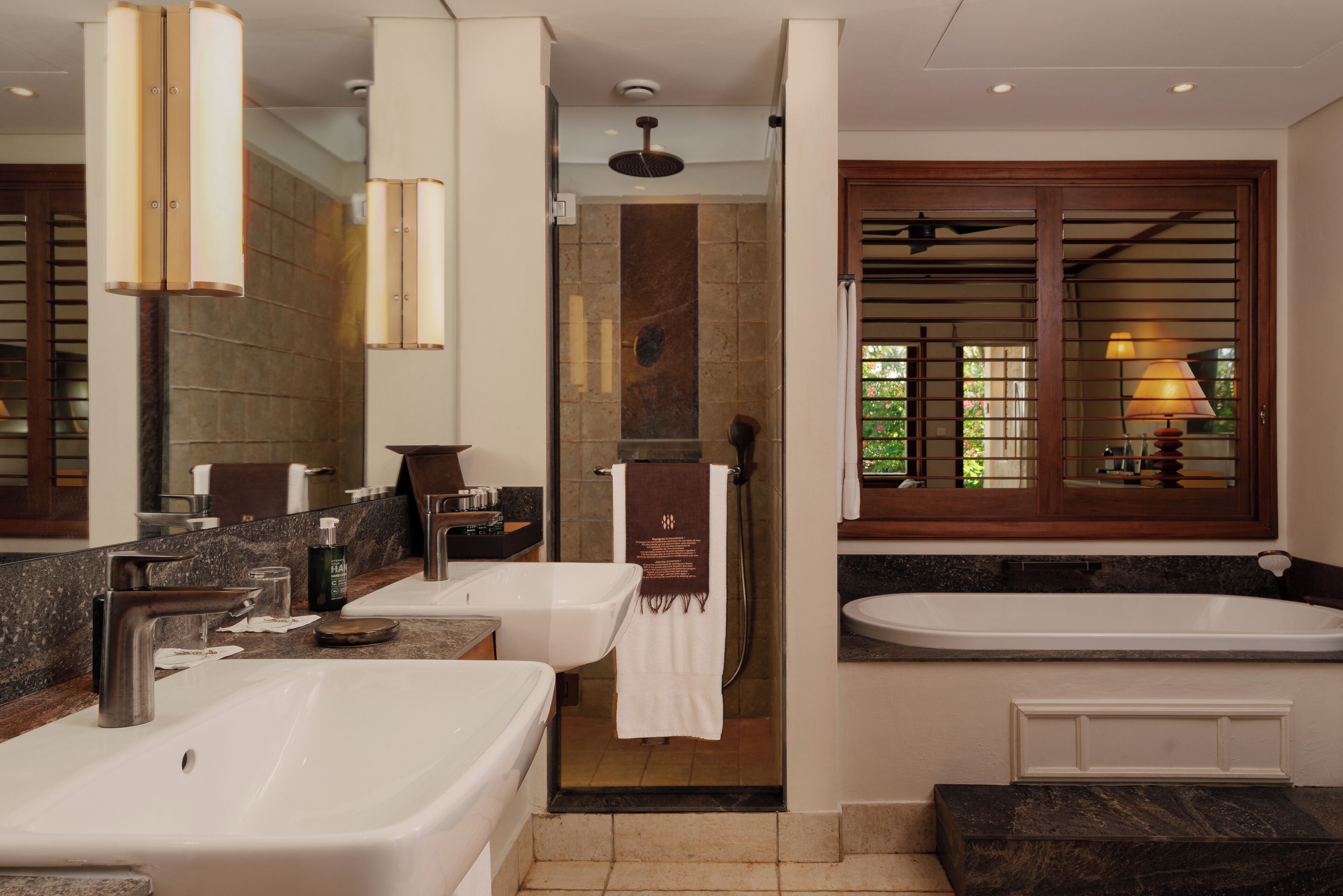 Un baño moderno con dos lavamanos, una bañera y una ducha.