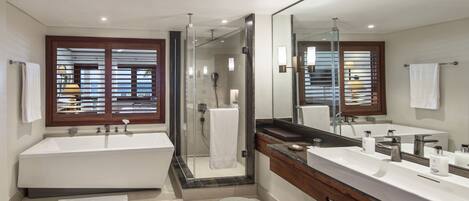 A modern bathroom with a large bathtub, a walk-in shower, and a vanity with a mirror.