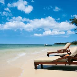 Relax in comfort on the beach with cushioned lounge chairs overlooking the calm ocean.