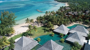 Un resort con varias construcciones tipo bungalow, una playa y un océano azul turquesa.