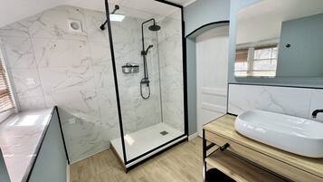 A modern bathroom with a glass-enclosed shower, a white sink, and a mirror above it.
