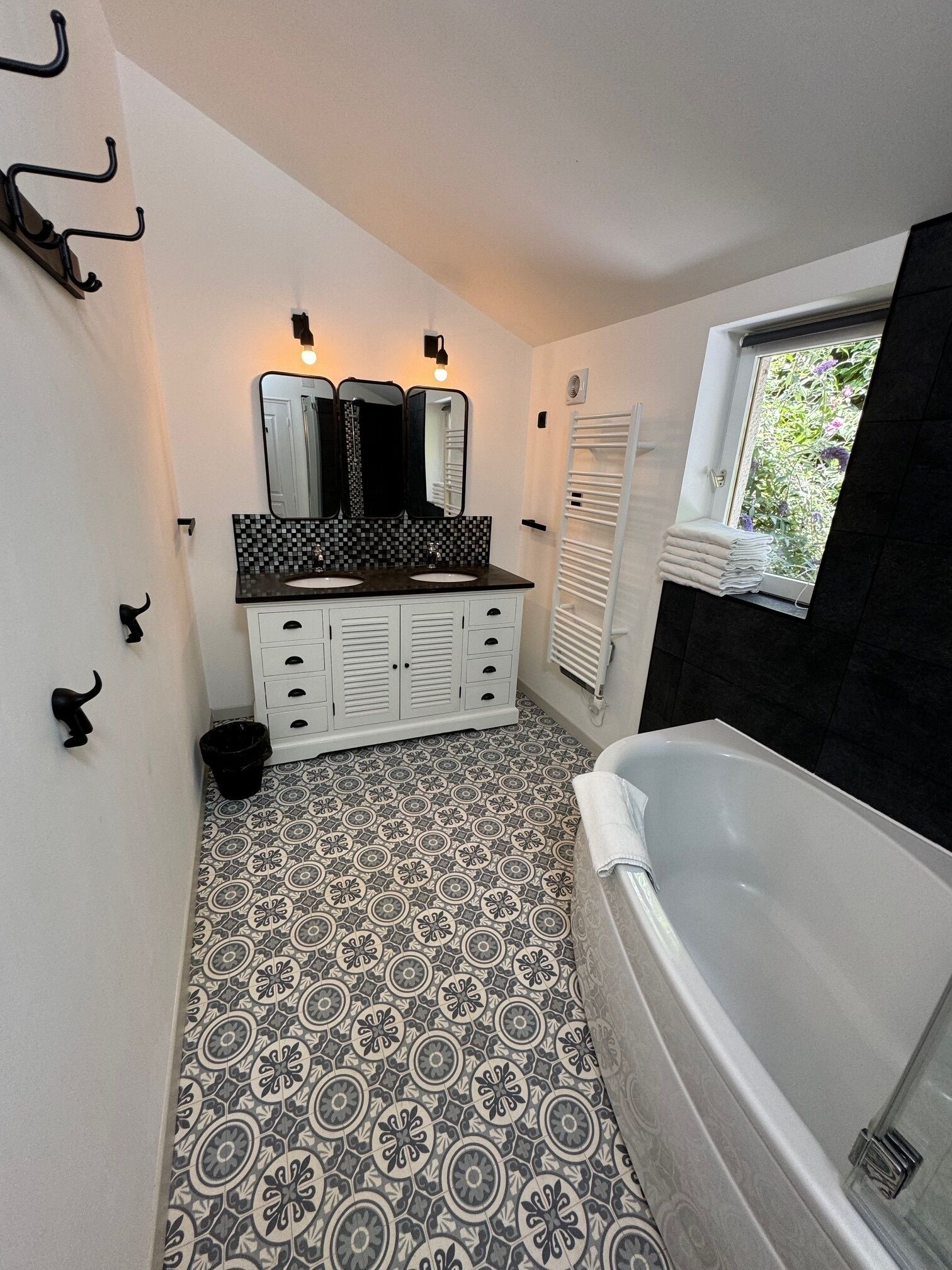 A bathroom with a black and white patterned floor, a white vanity with a mirror, and a bathtub.