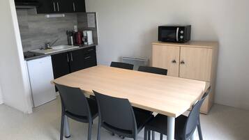 Una cocina compacta con una mesa y sillas, un microondas y un refrigerador pequeño.