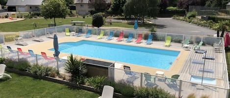 Una piscina con varias sillas de descanso y una terraza.