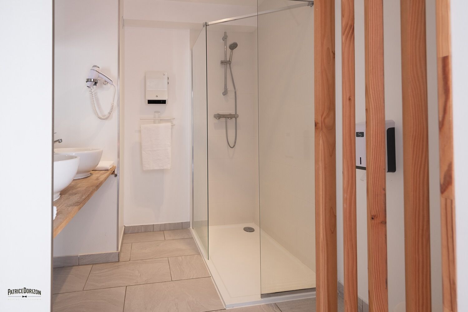 Une salle de bain moderne avec une douche à parois de verre, un meuble-lavabo en bois et un porte-serviettes.