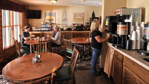 A restaurant with wooden tables and chairs, a coffee machine, and a counter with a menu. - Boarders Inn & Suites by Cobblestone Hotels – Waukon (Waukon)