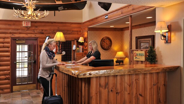 A wooden reception desk with a clock and a 'No Smoking' sign. - Boarders Inn & Suites by Cobblestone Hotels – Waukon (Waukon)