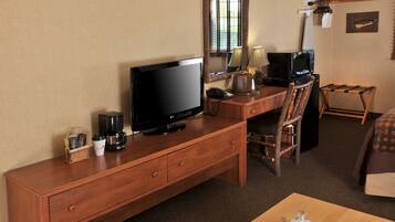Une chambre d’hôtel avec un bureau en bois, un téléviseur à écran plat, une machine à café et une petite table avec un jeu d’échecs.