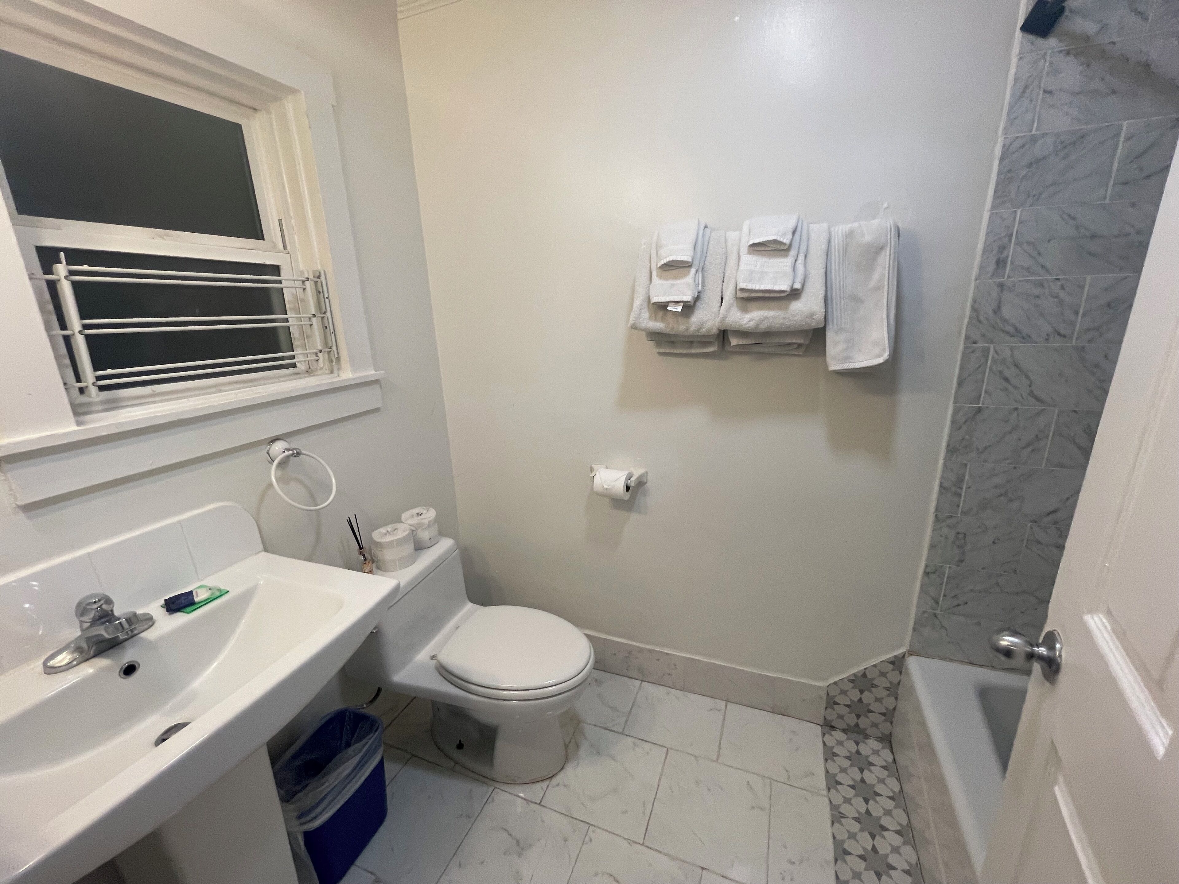 A bathroom with a toilet, sink, and shower. There are towels hanging on the wall.
