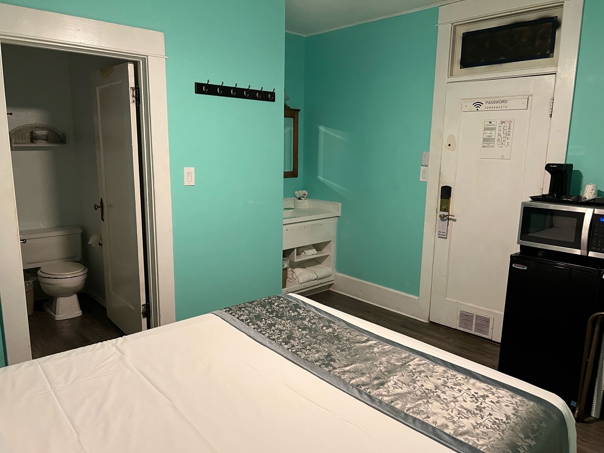 Ein Schlafzimmer mit Bett, ein Badezimmer mit Toilette und eine Küchenzeile mit Mikrowelle.