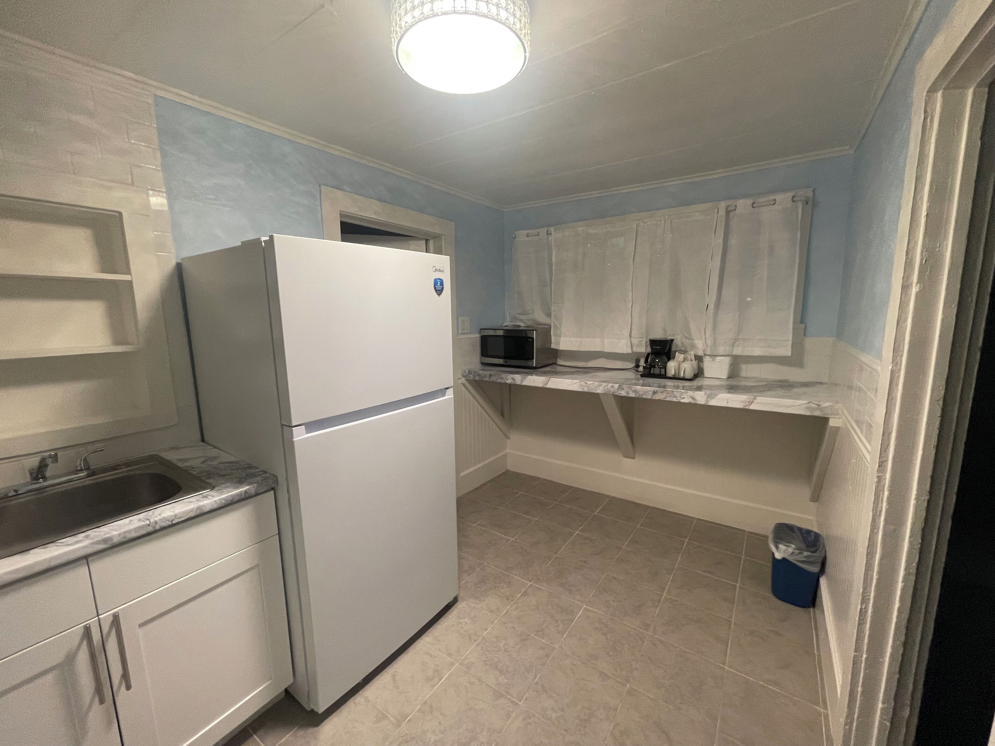 A compact kitchen with a refrigerator, microwave, and coffee maker on the countertop.