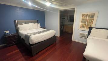 Ein Hotelzimmer mit einem großen Bett, einem Nachttisch, einem Deckenventilator und Blick zur Küche.