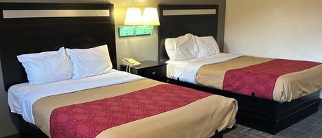 A hotel room with two beds, each with a headboard, a nightstand with a lamp, and a telephone.