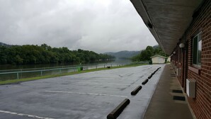 A covered parking area with a view of a river and forested hills. - Budget Host Inn Charleston (Charleston)
