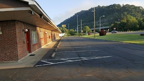 A motel with a brick facade, a parking lot, and a mountainous backdrop. - Budget Host Inn Charleston (Charleston)