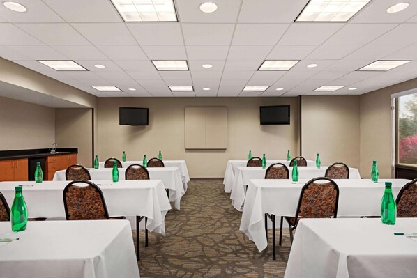 Un salón de conferencias con mesas, sillas y botellas verdes.
