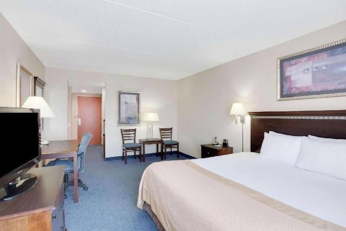 Una habitación de hotel con cama, escritorio, televisor y sillas.