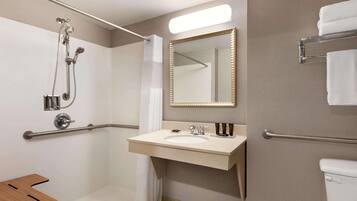 Een moderne badkamer met een douche, wastafel, spiegel en toilet.