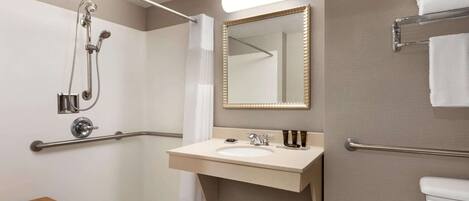 A modern bathroom with a shower, a sink, a mirror, and a toilet.